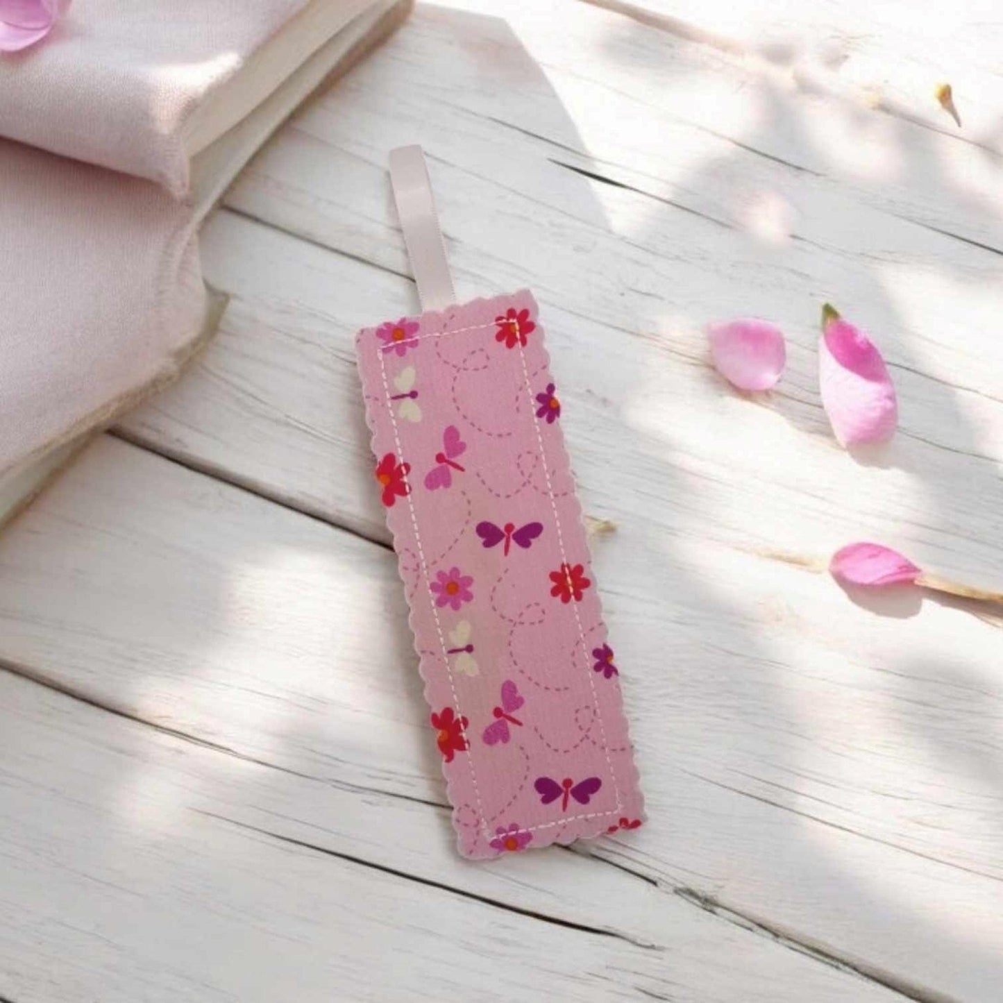 A pink bookmark with pink butterflies and flowers. The bookmark has a pale pink ribbon loop attached.